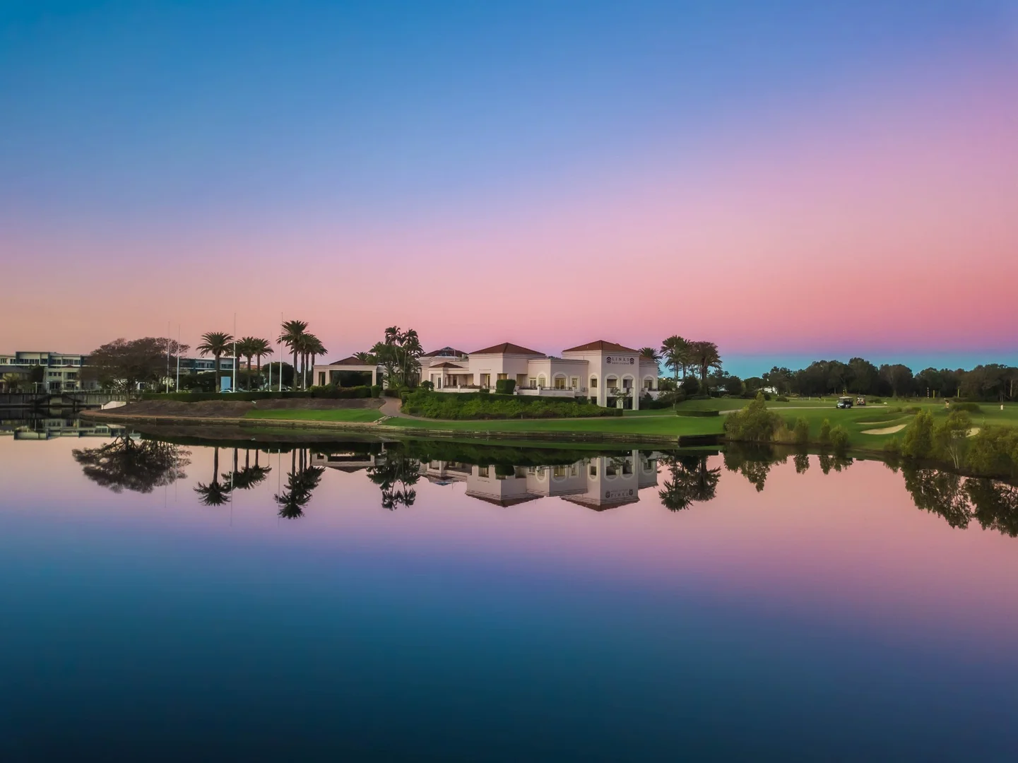 Links Golf & Wellbeing Gold Coast clubhouse at dusk with reflection on water